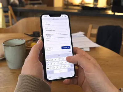 Hands holding a phone while filling out a form